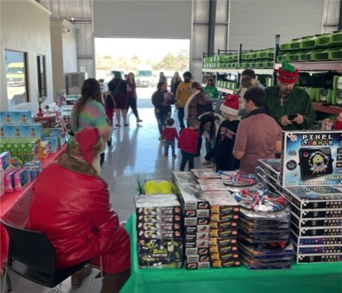 People in warehouse and tables full of toys.